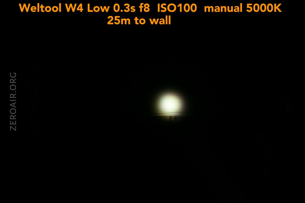 A small, bright white light appears in the center of a black background. Yellow text at the top provides camera and lighting specs: “Weltool W4 Low 0.3s f8 ISO100 manual 5000K 25m to wall.” The left side reads “ZEROAIR.ORG.”