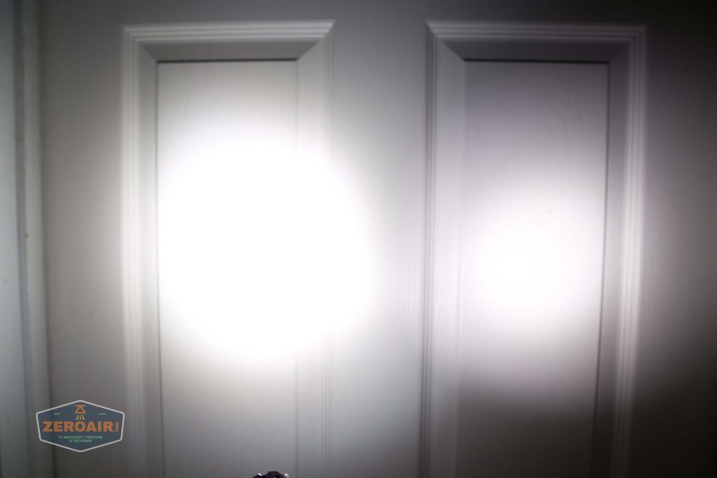 A white door with two vertical panels is illuminated by two bright, circular flashlight beams. There is a small logo with the text ZEROAIR in the lower left corner.