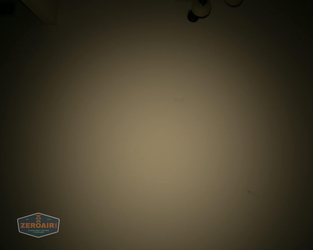 A dimly lit beige wall with a ceiling light fixture partially visible in the top right corner and a small ZeroAir logo in the bottom left corner.