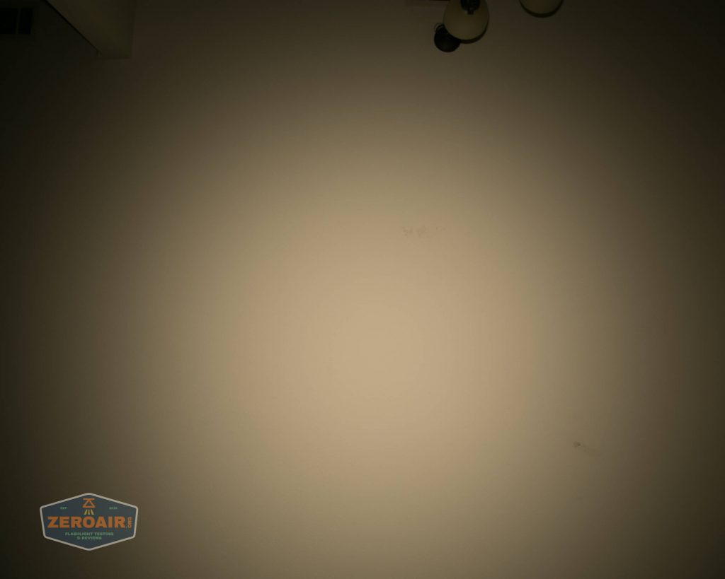 A dimly lit, plain beige wall with a small, round ceiling light fixture partially visible at the top right and a ZeroAir logo in the bottom left corner.