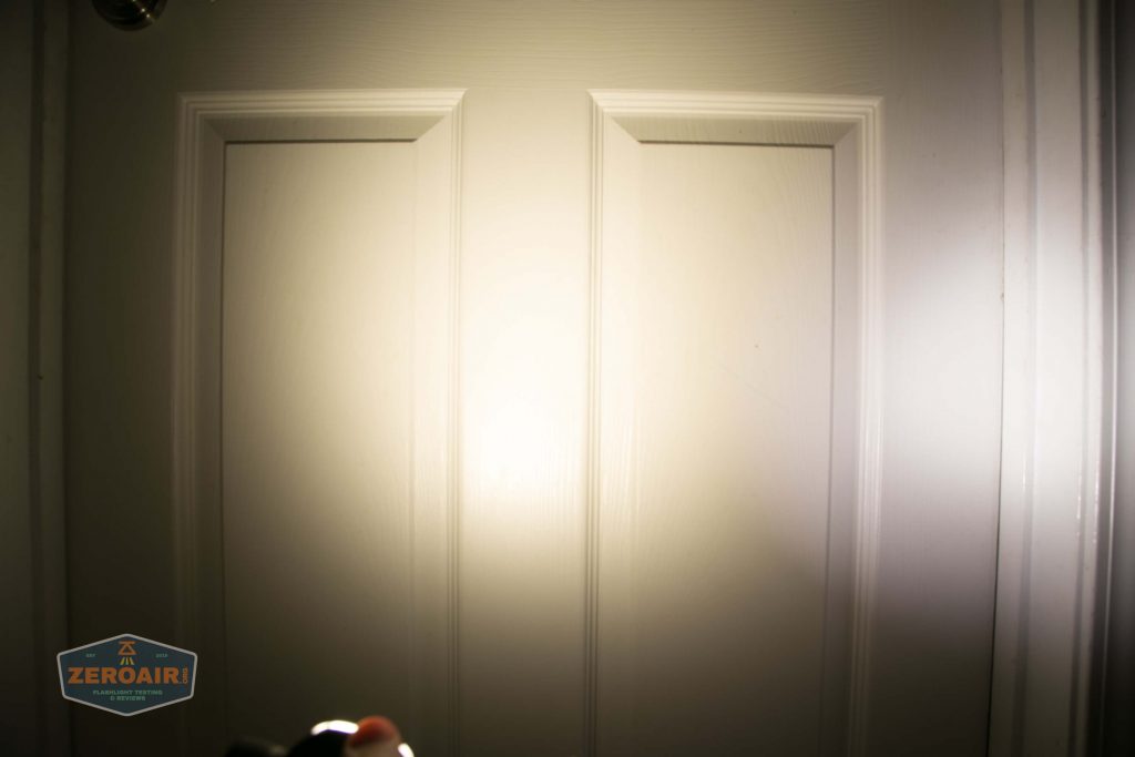 A white paneled door is illuminated by a bright light source, creating a circular area of intense brightness in the center. The ZeroAir logo is visible in the bottom left corner.