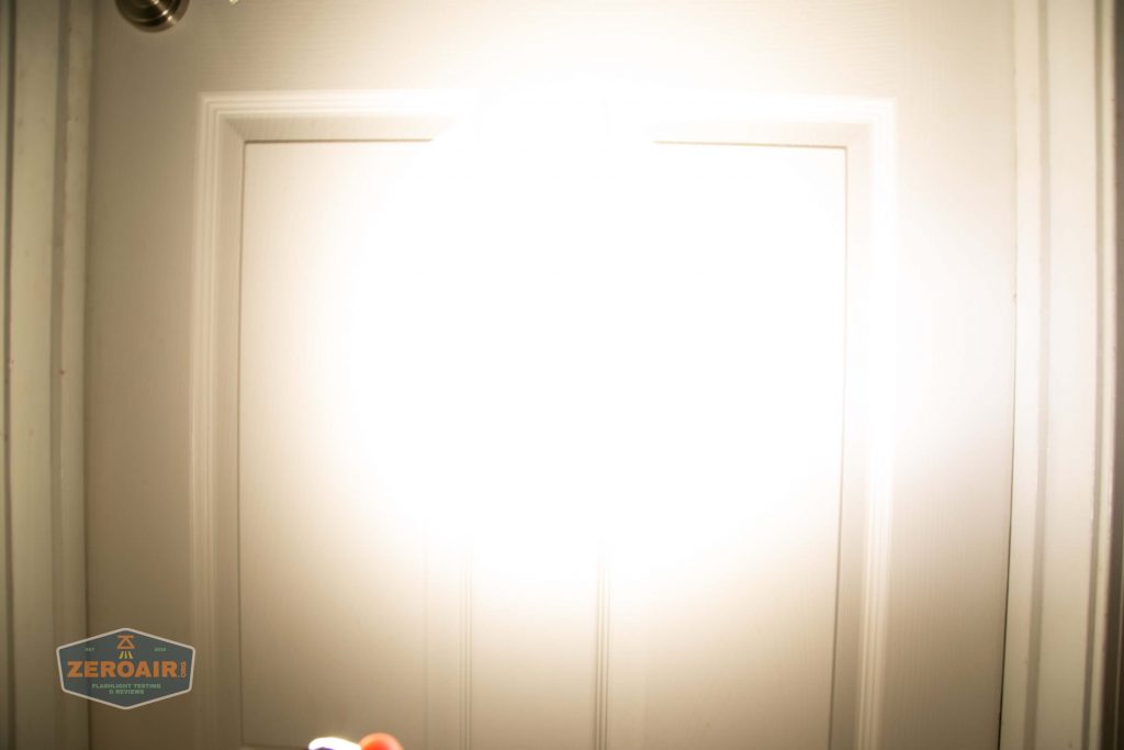 A door is illuminated by a bright light, causing overexposure in the center of the image. A small ZEROAIR logo appears in the lower left corner. Door details are partially visible around the edges.
