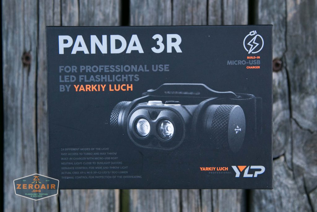A black box labeled PANDA 3R containing a headlamp for professional use, with branding by Yarkiy Luch and YLP. Text highlights features such as a micro-USB charger and LEDs. The box rests on a wooden surface.