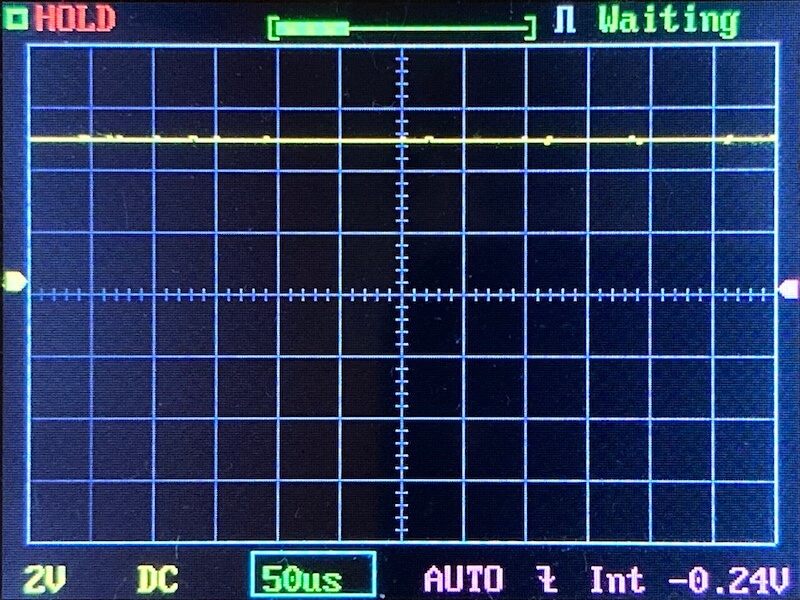 Oscilloscope screen displaying a near-flat horizontal yellow line slightly below center, grid background, and text indicators including 2V, DC, 50µs, AUTO, Int -0.24V, HOLD, and Waiting.