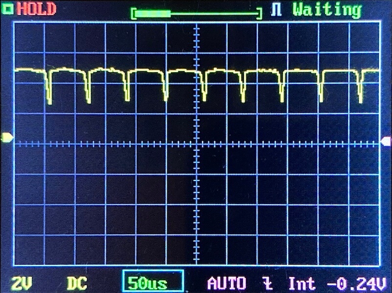 Oscilloscope display showing a repeating waveform with regular downward spikes. The horizontal scale is set to 50 microseconds per division, and the vertical scale is 2 volts per division. The status reads Waiting.