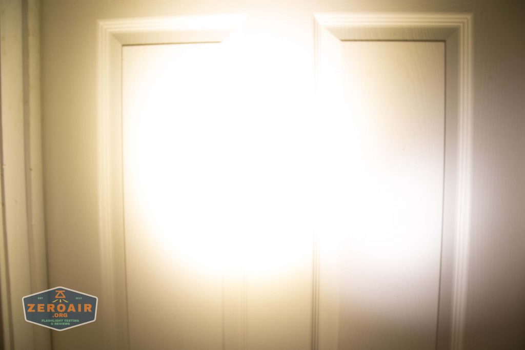 A bright flashlight beam shines directly onto a closed double-panel door, washing out the center area with intense light. A logo reading ZeroAir.org appears in the lower left corner.