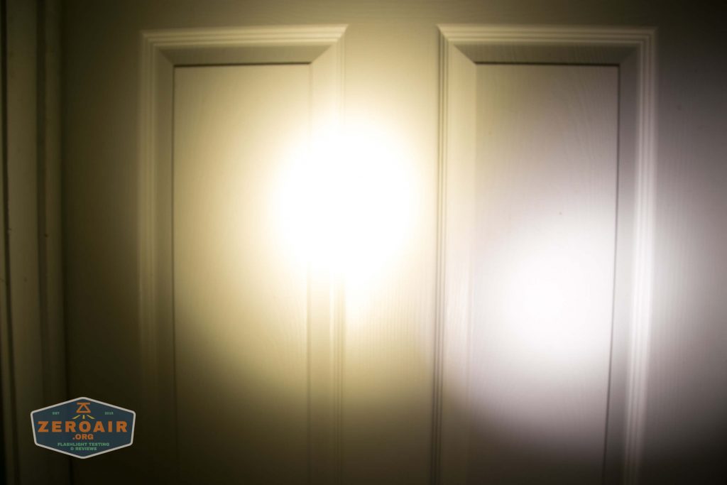 A white door illuminated by a bright beam of light in the center, creating a glare. A logo reading ZeroAir.org is visible in the lower left corner of the image.