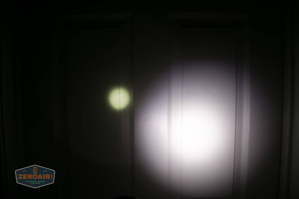 A dimly lit white door is illuminated by two flashlight beams: a small, circular yellowish spot on the left and a larger, bright white spot on the right. A ZEROAIR logo is visible in the lower left corner.