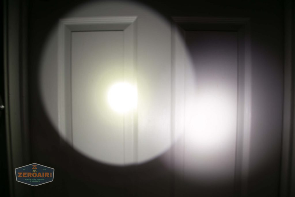 A white door with another door beside it is illuminated by the bright circular beam and spill of a flashlight. There is a ZeroAir watermark in the lower left corner of the image.