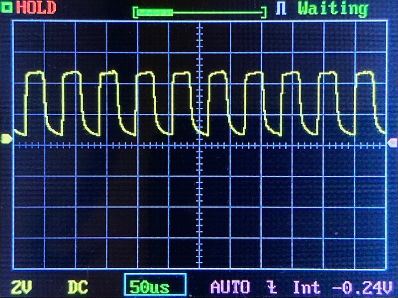 A digital oscilloscope screen displays a periodic waveform with a repeating, jagged pattern. The horizontal scale is 50 microseconds per division, and the vertical scale is 2 volts per division.