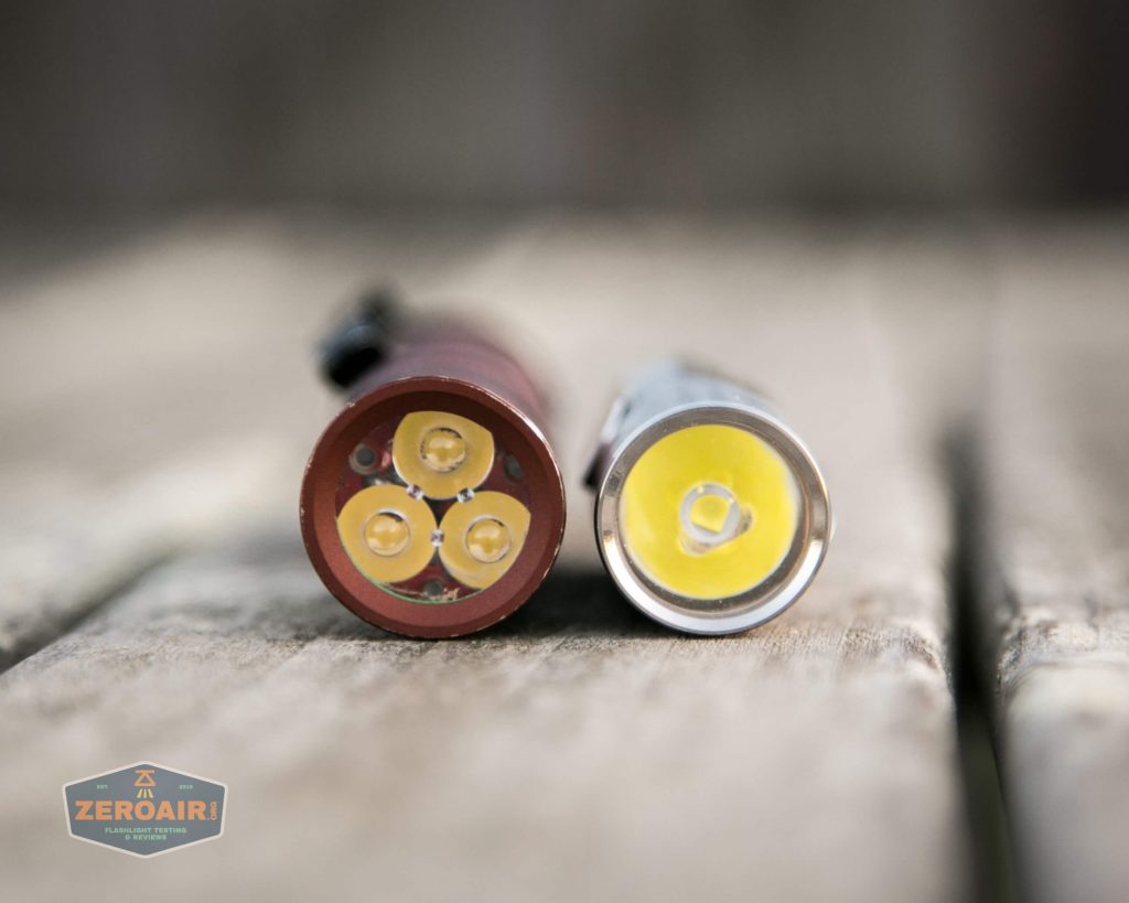 Two flashlights shown lying side by side on a wooden surface, with their LED bulbs facing the camera. The left flashlight has four small LEDs, while the right one has a single larger LED. A logo reading ZeroAir is in the bottom left corner.