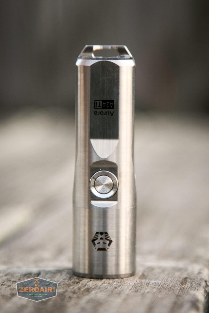 A stainless steel flashlight stands upright on a wooden surface. It has a round button on the front and the text “Autora 4211” above the button. The ZeroAir logo appears in the bottom left corner.