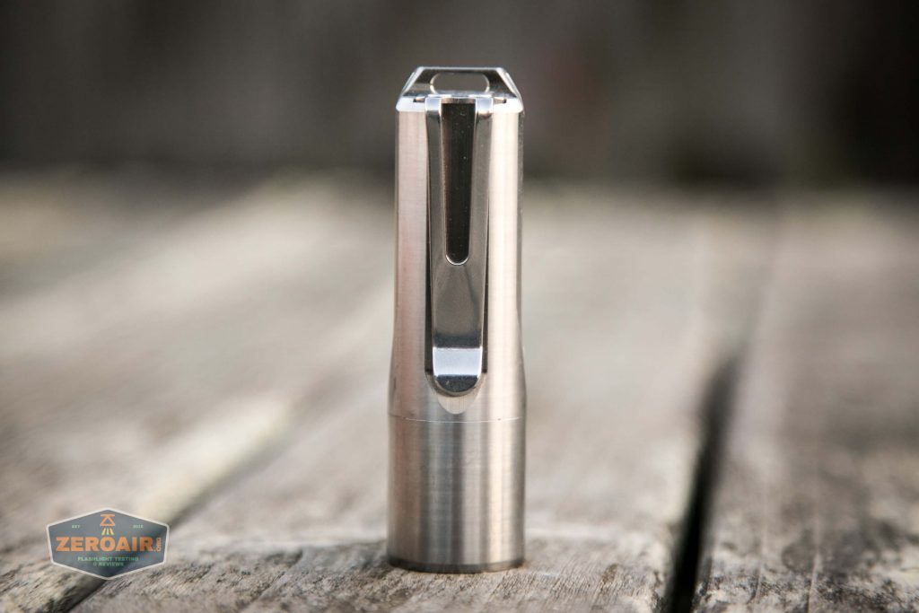 A stainless steel, cylindrical metal object with a slot and angled top is positioned upright on a weathered wooden surface. A ZeroAir logo appears in the lower left corner.