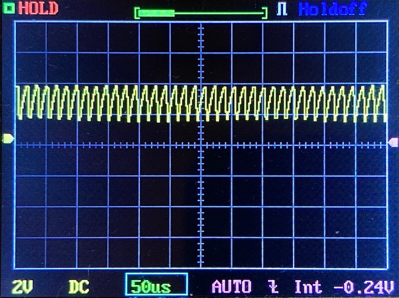 Oscilloscope screen displaying a repeating yellow waveform with a regular, spiked pattern. The horizontal scale is set to 50 microseconds per division, and the vertical scale is 2 volts per division.