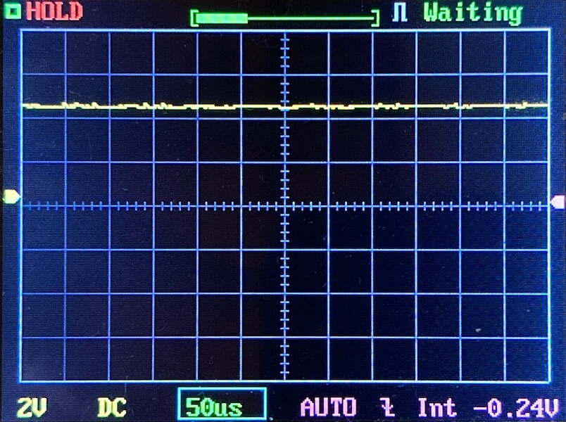Oscilloscope screen displaying a mostly flat yellow waveform near the zero line, indicating little signal variation. The settings show 2V per division, 50 microseconds per division, DC coupling, and average voltage of -0.24V.