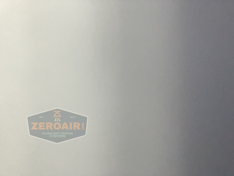 A plain, smooth light gray surface with a semi-transparent “ZeroAir” logo and text reading “Flashlight Testing & Reviews” in the bottom left corner.