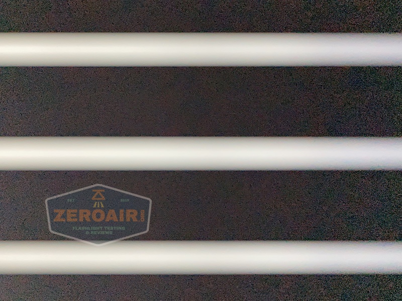A close-up photo of four horizontal white bars on a dark background, with a semi-transparent ZeroAir.net logo visible in the lower left corner.