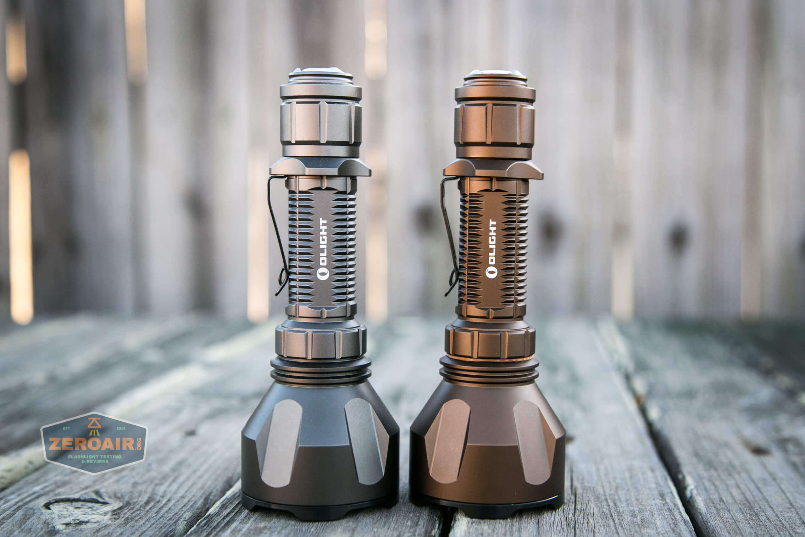 olight warrior x turbo desert tan flashlight beside gunmetal grey