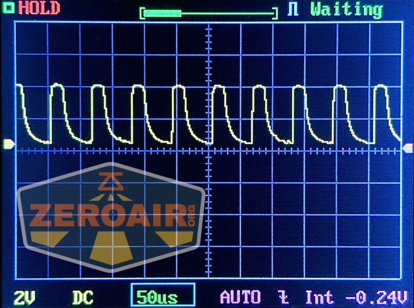 A digital oscilloscope screen displays a repeating waveform with sharp peaks and gradual slopes. The settings show 2V per division vertically and 50 microseconds per division horizontally. The ZeroAir logo is overlaid on the left.