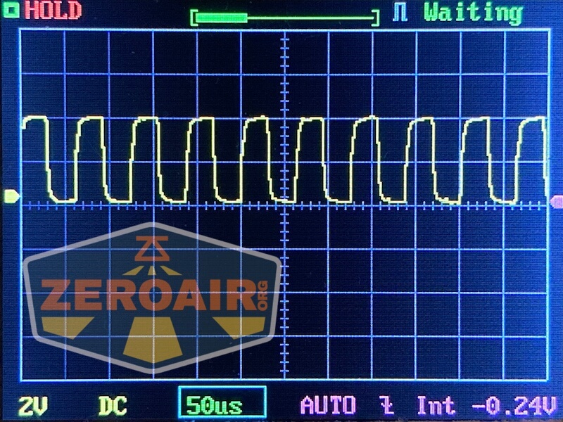 A digital oscilloscope display shows a yellow square waveform signal with measurement settings: 2V/div vertical, 50µs/div horizontal, DC coupling, and AUTO trigger mode. The ZeroAir logo is visible in the lower left.