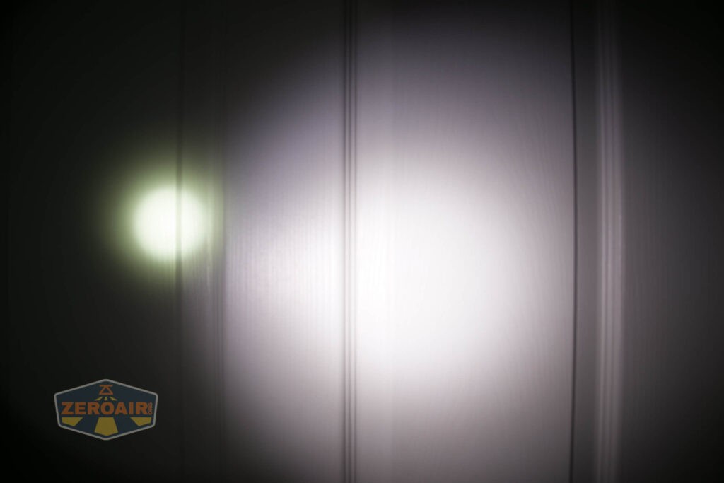 A white flashlight beam and a smaller, dimmer green circle are projected on a vertically paneled wall; a logo with the text ZeroAir is in the lower left corner.
