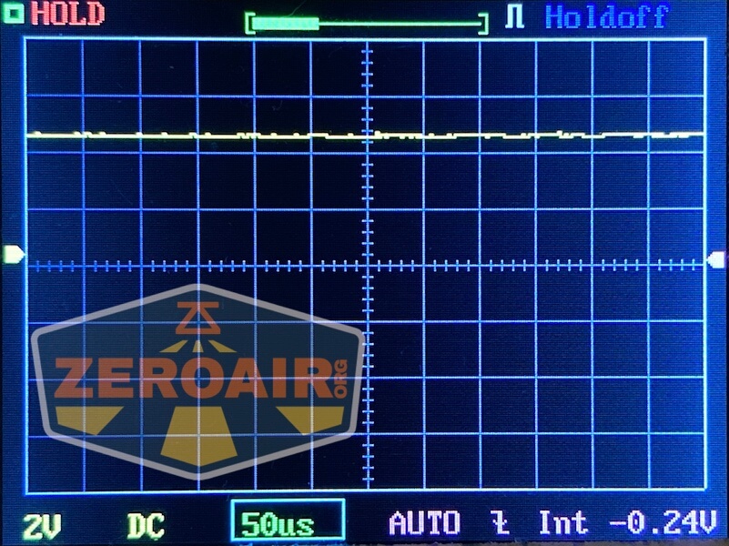 Oscilloscope screen displaying a mostly flat yellow waveform near zero voltage. Grid lines and measurement markers are visible, with settings showing 2V, 50 microseconds, and -0.24V. A Lumintop GT Nano Brass logo is overlaid in the lower left.