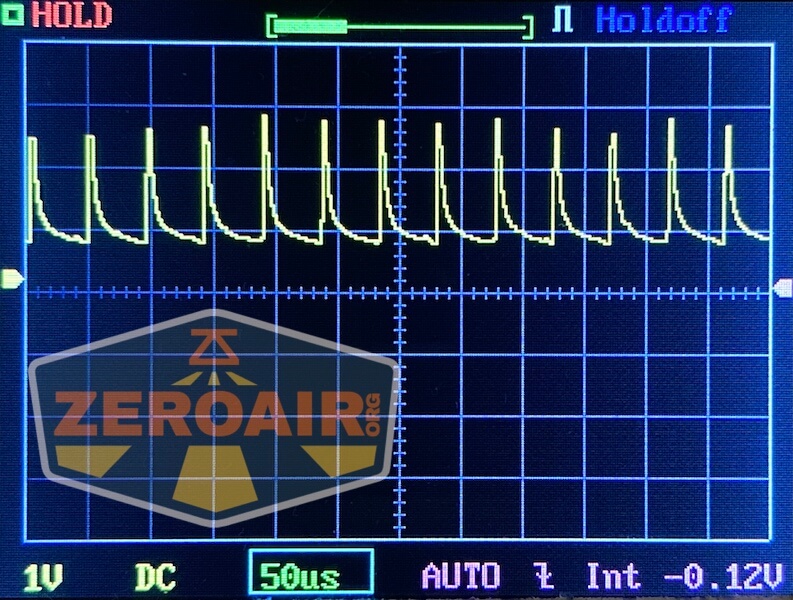 An oscilloscope screen shows a repeating yellow waveform with sharp peaks and regular intervals. The time base is set to 50 microseconds per division. A semi-transparent ZEROAIR logo overlays the lower left corner.