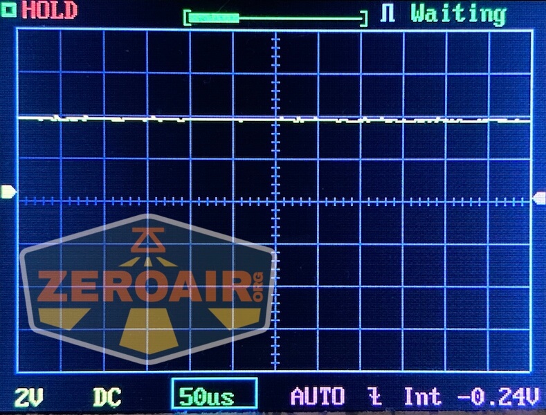 An oscilloscope screen displaying a mostly flat yellow signal trace at 2V and 50 microseconds per division. The words “ZEROAIR.org” appear in a translucent logo overlay in the bottom left corner.