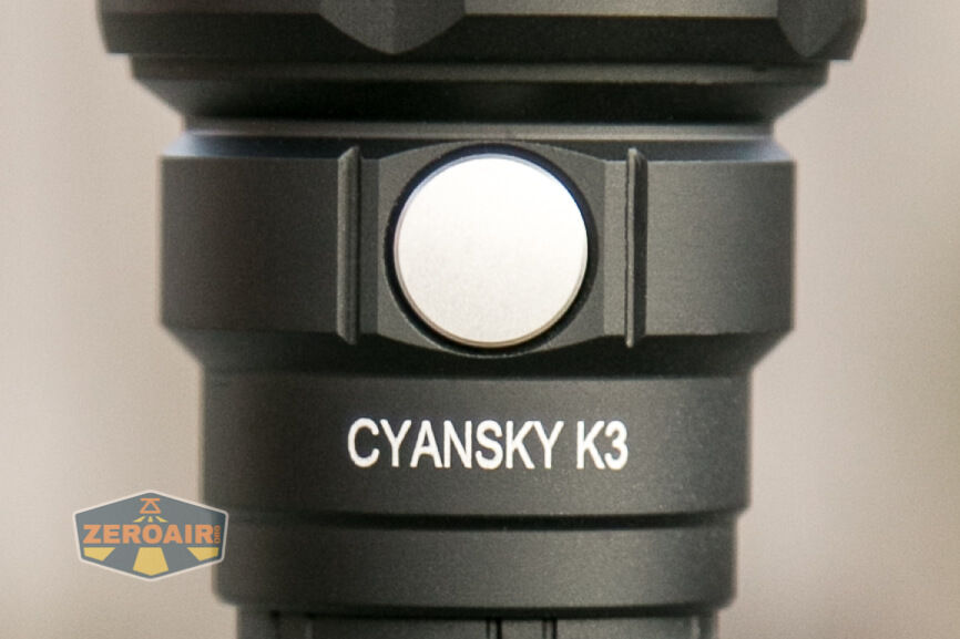 Close-up of a black flashlight with CYANSKY K3 labeled on the body. A round silver button is visible above the text. A ZeroAir logo is in the lower left corner.
