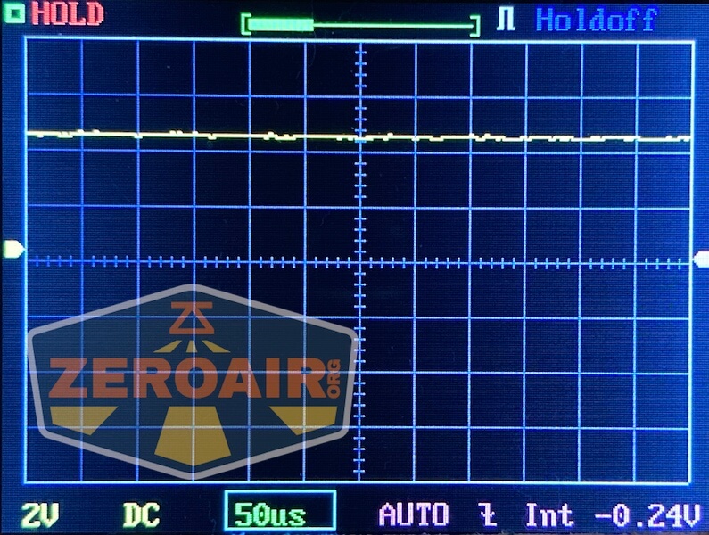 Oscilloscope display shows a mostly flat yellow waveform with minor fluctuations, grid lines, and measurement settings at the bottom. A semi-transparent “ZEROAIR.org” logo is overlaid on the left side.