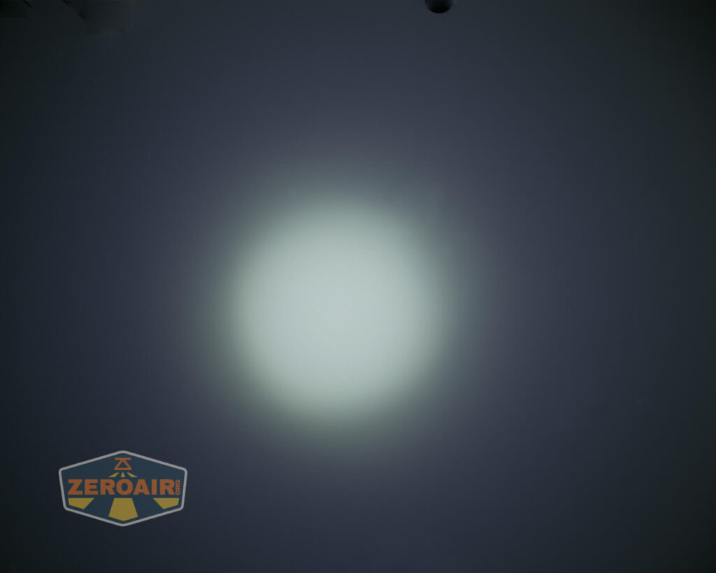 A circular, bright white light beam is shown centered against a dark background. The lower left corner features a logo with the word ZEROAIR in yellow letters on a dark shield shape.