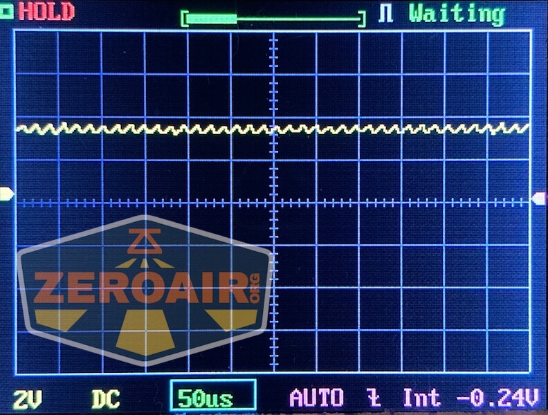 An oscilloscope screen displays a mostly flat yellow waveform with minor fluctuations. The screen shows Waiting in the top right and settings of 2V, 50µs, AUTO, and -0.24V. The ZeroAir logo is visible on the left.