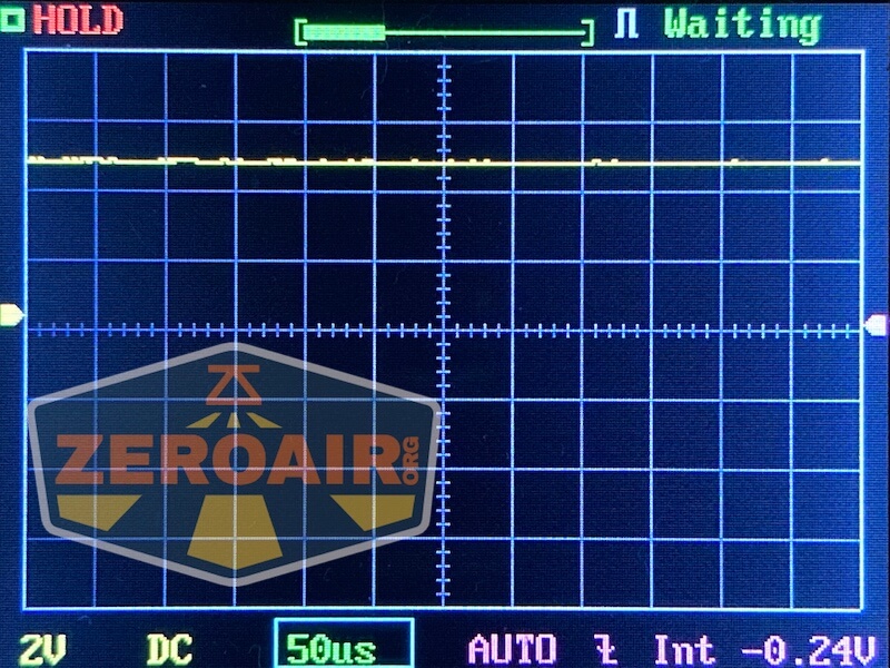 Oscilloscope screen shows a mostly flat yellow signal line near zero volts, with settings at 2V/div and 50 microseconds/div. The display reads “HOLD” and “Waiting.” A semi-transparent ZeroAir logo covers part of the screen.