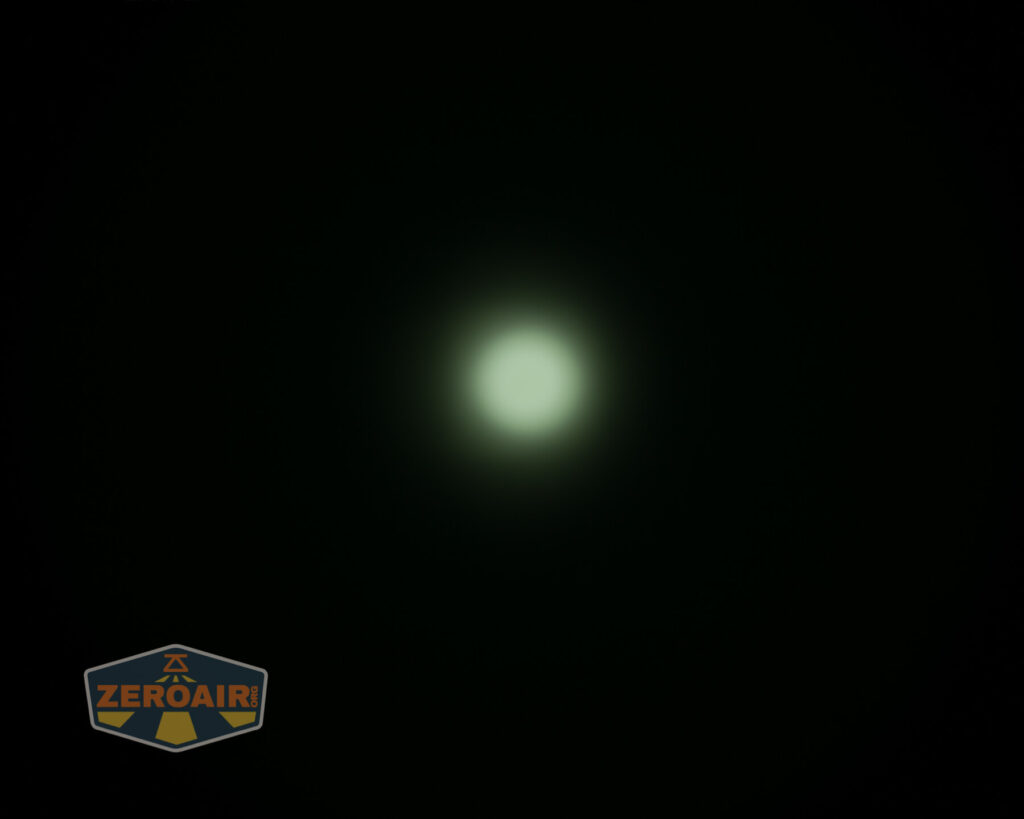 A bright white circular light source is centered against a dark background. A logo reading ZeroAir appears in the lower left corner.