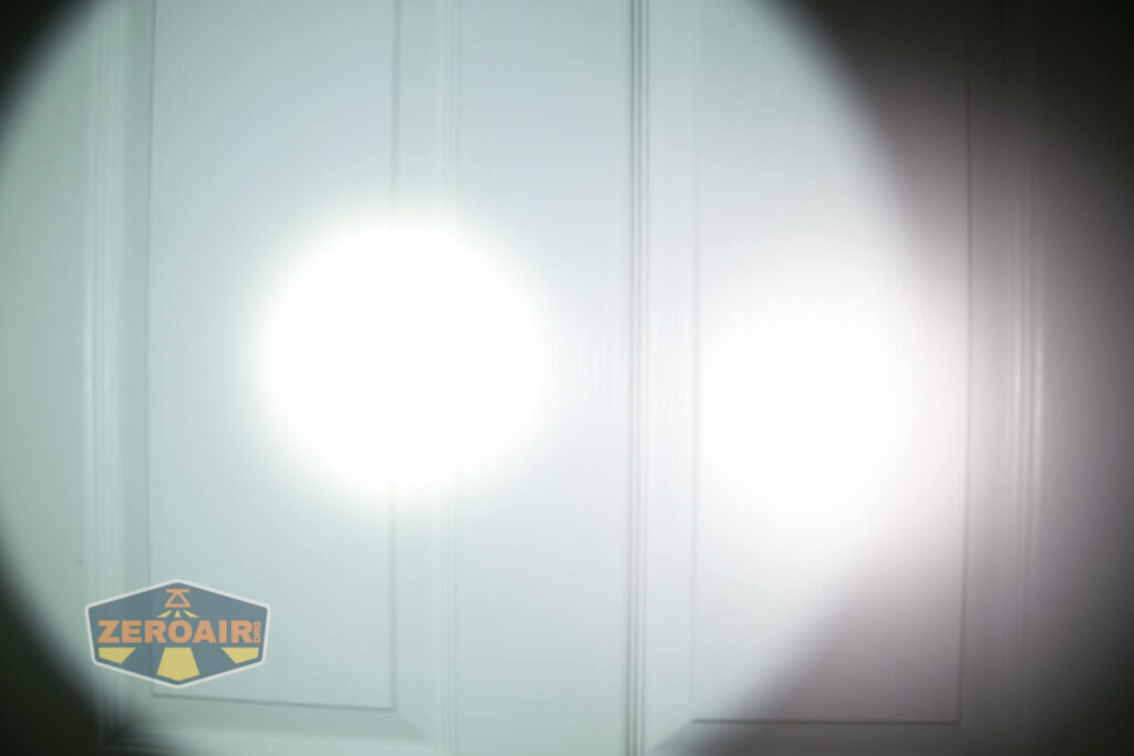A white flashlight beam shines on a closed white paneled door, creating a bright circular spot of light. A logo with the word “ZeroAir” appears in the bottom left corner.