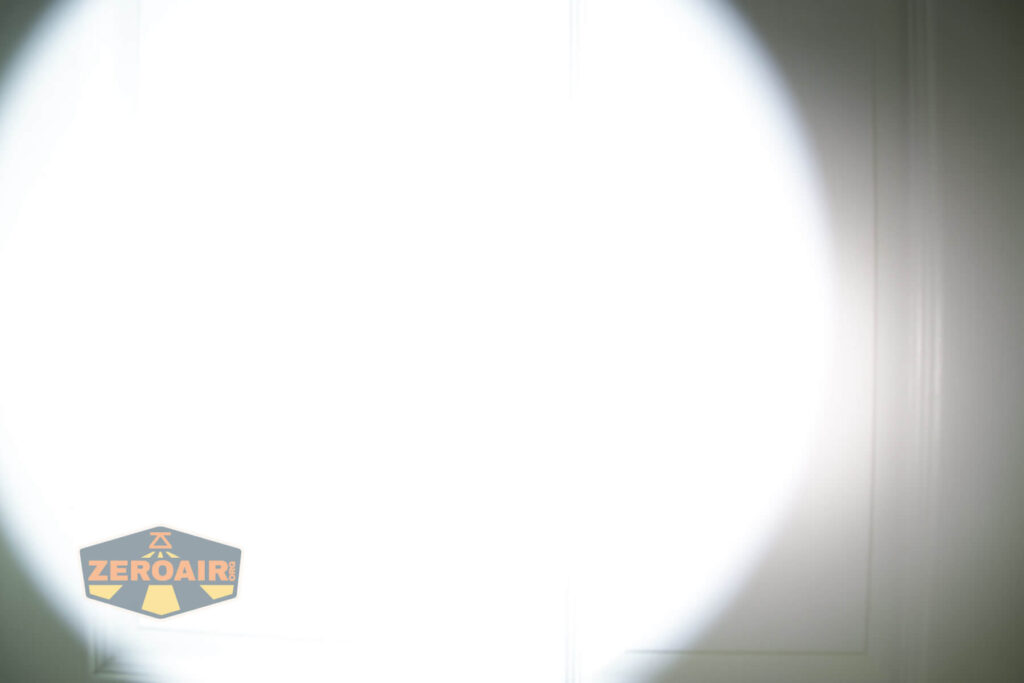 A bright white flashlight beam illuminates the center of a white door, with the ZeroAir logo visible in the lower left corner of the image.