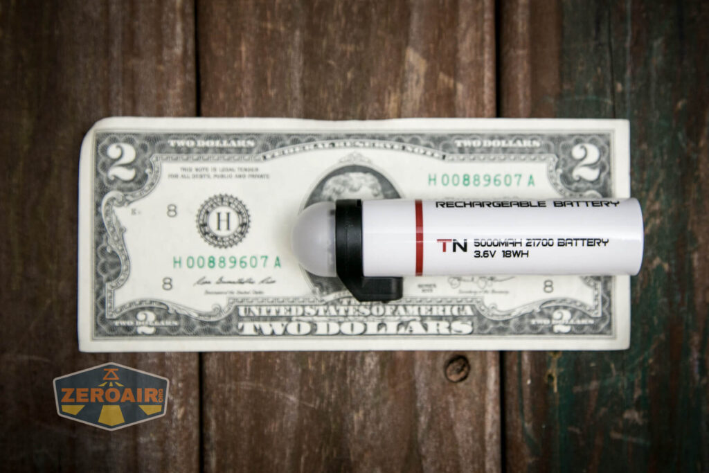 A rechargeable battery labeled 5000mAh 21700 battery 3.6V 18Wh is placed on top of a U.S. two-dollar bill. The ZeroAir logo appears in the bottom left corner of the image.
