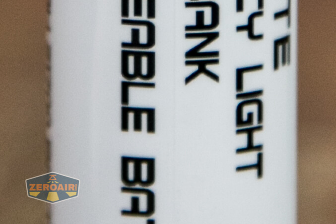A close-up of a cylindrical white object with black, vertically oriented text that reads RECHARGEABLE BATTERY LIGHT BANK. A small logo with the text ZEROAIR appears in the bottom left corner.