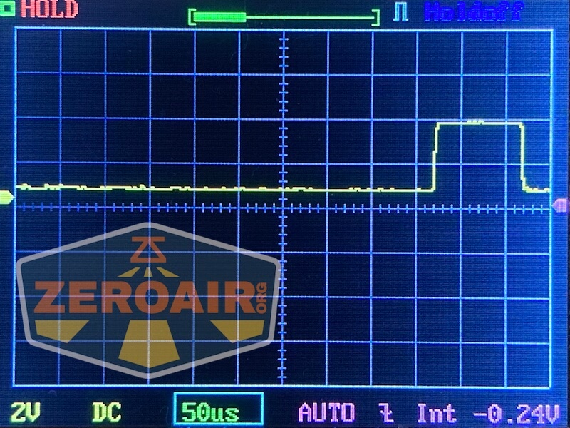 Oscilloscope screen showing a square waveform signal with one prominent pulse. The display reads 2V, DC, 50µs per division. The ZeroAir logo is partially visible in the lower left corner.