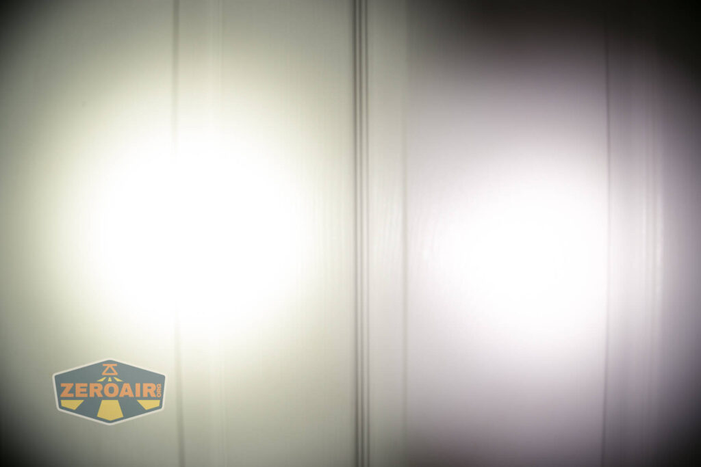 Two round beams of light are projected onto a white paneled surface, with a logo reading ZeroAir in yellow and black in the lower left corner. The left beam appears warmer; the right beam is cooler in tone.