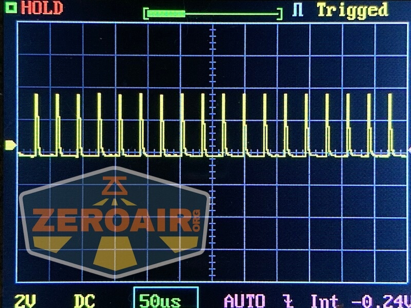 Oscilloscope screen displaying a repeating square wave signal with markers and gridlines; the display includes “HOLD,” “Triggered,” “2V DC,” and “50μs” settings along with a ZeroAir logo watermark.