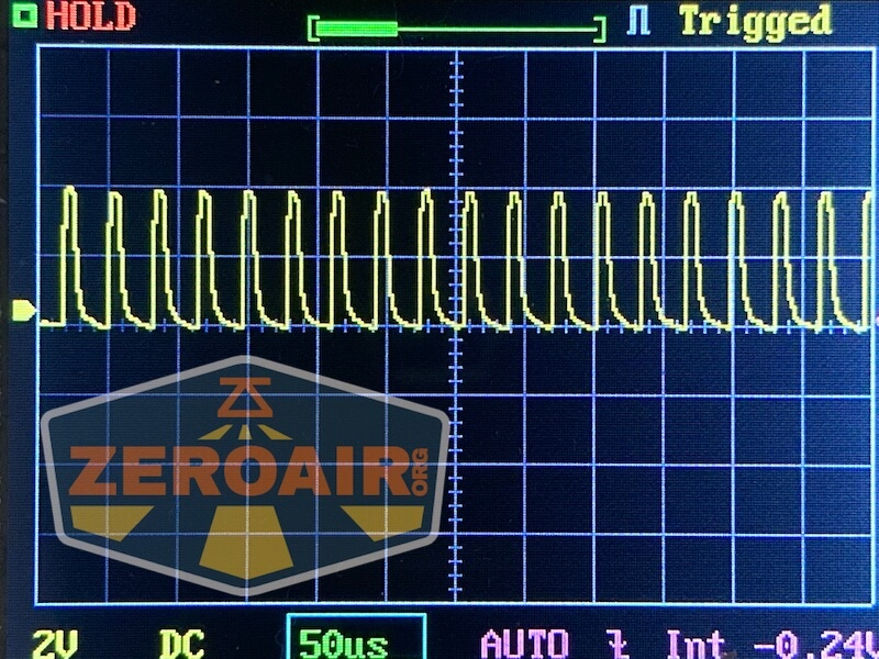 An oscilloscope screen displays a repeating yellow waveform pattern. The settings show 2V per division, 50 microseconds per division, and DC coupling. An overlaid ZeroAir logo appears in the lower left corner.