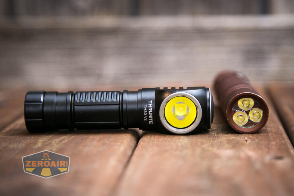 A black Thrunite flashlight with a side button is lying on a wooden surface next to its cylindrical battery, exposing three yellow battery contacts. A ZeroAir logo is visible in the bottom left corner.