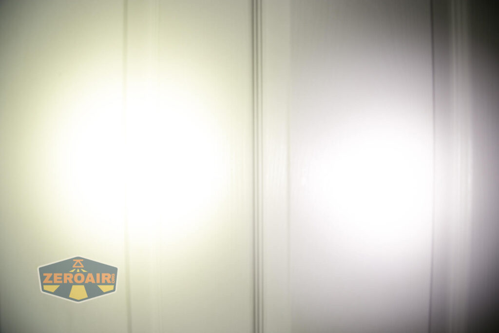 Two beams of white light are projected onto a white paneled door, creating bright circular spots. There is a logo with the text ZeroAir in the bottom left corner of the image.