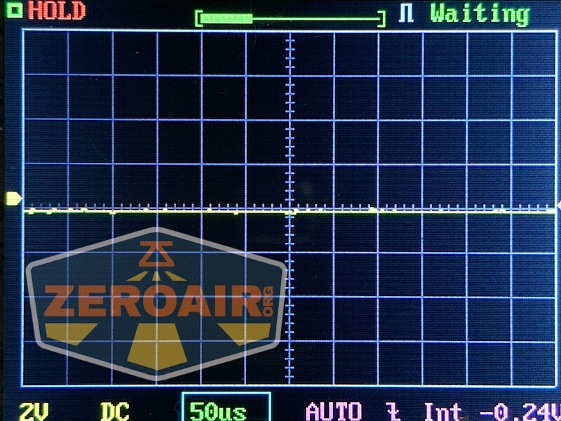 A digital oscilloscope screen displays a flat horizontal trace, with HOLD in red at the top left and Waiting in green at the top right. Measurement and setting data appear along the bottom and sides. A ZeroAir.org watermark is visible.