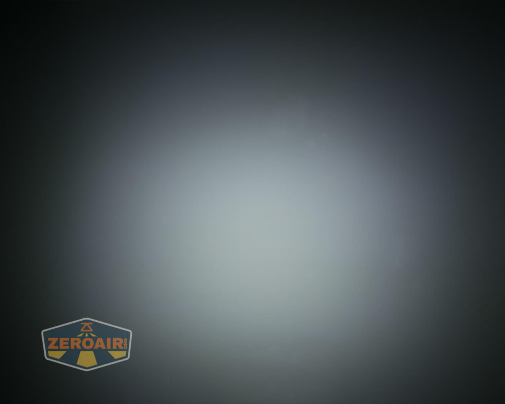 A circular, diffused white light beam is cast against a dark grey background. A ZEROAIR logo appears in the lower left corner of the image.