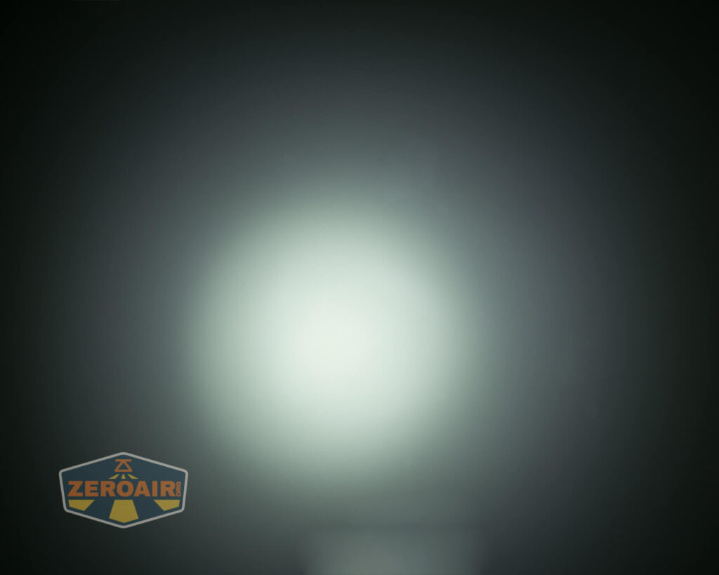 A circular white beam of light is centered on a dark background, creating a gradient effect from bright in the middle to dim at the edges. A logo reading ZEROAIR is in the lower left corner.