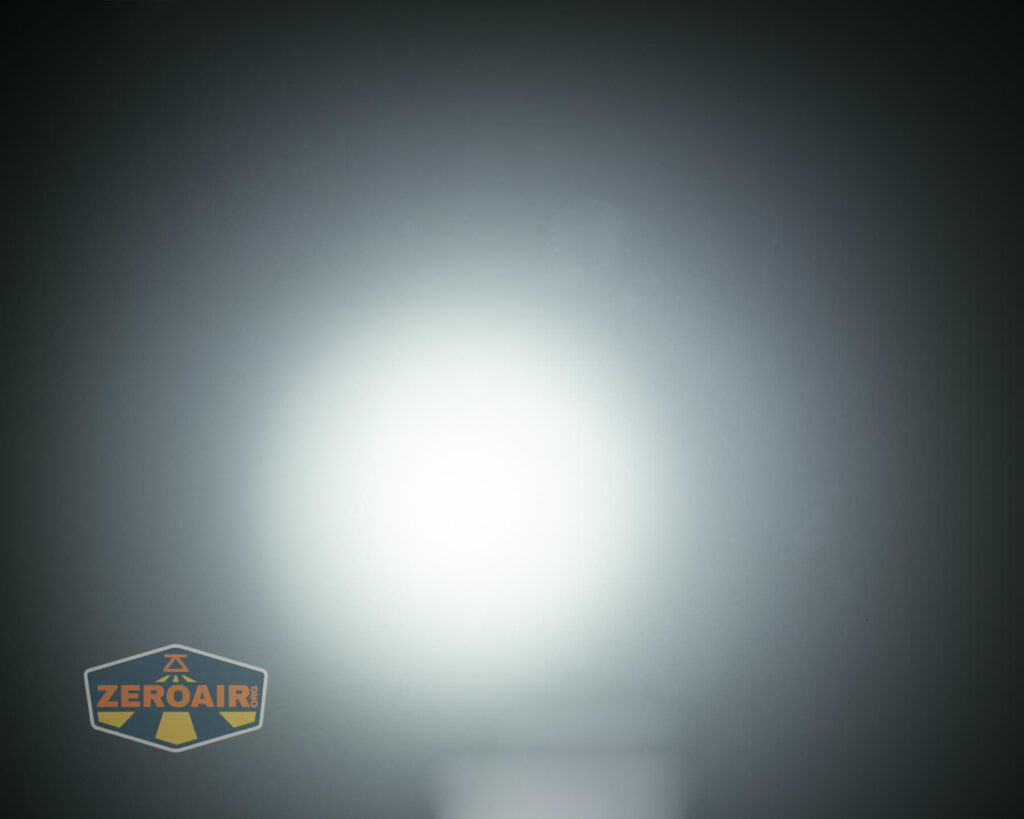 A bright white circular light beam is centered against a dark background, creating a gradient effect. A ZeroAir logo is in the lower left corner of the image.