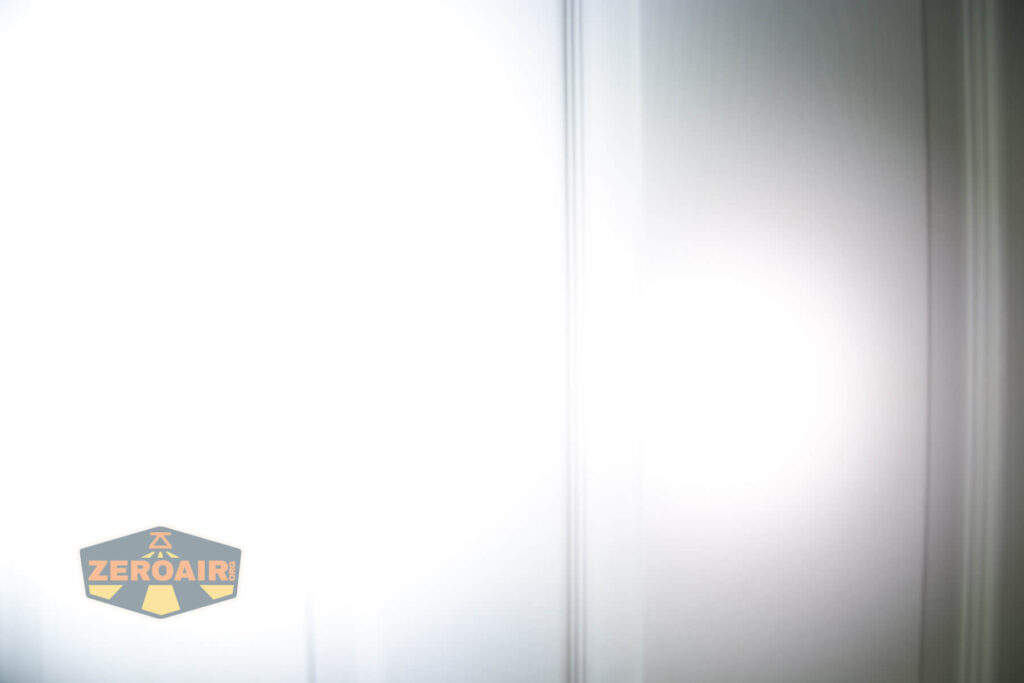 A bright white light shines on a white paneled surface, creating a soft gradient. The ZeroAir logo appears in the lower left corner.