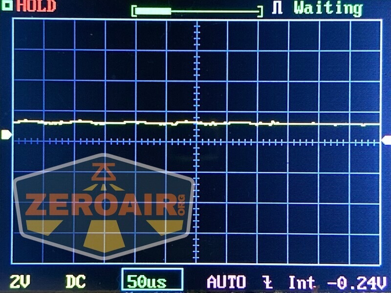 Oscilloscope screen showing a mostly flat yellow waveform near zero, indicating little or no signal activity. The display includes grid lines, scale information, and the logo ZEROAIR.org in the lower left corner.